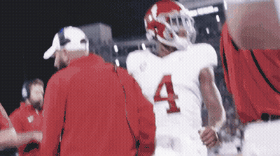 A Football Player Wearing A White Jersey With The Number Four On It GIF