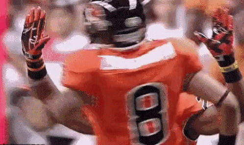 A Football Player Wearing An Orange Jersey With The Number 8 GIF