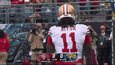 A Football Player Wearing Number 11 Stands In Front Of A Scoreboard GIF