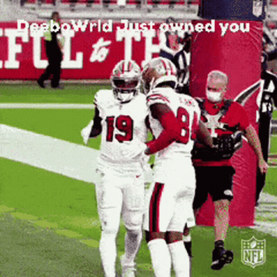 A Football Player Wearing Number 19 Is Hugging Another Player On The Field GIF