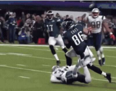A Football Player Wearing The Number 86 Is Being Tackled By Another Player GIF