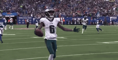 A Football Player With His Arms Outstretched Is Holding A Football On A Field . GIF