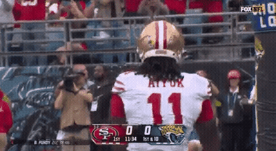 A Football Player With The Number 11 On His Jersey Stands In Front Of A Scoreboard . GIF