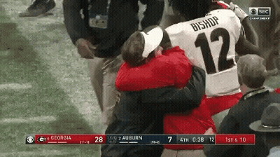 A Football Player With The Number 12 On His Jersey Is Hugging Another Player GIF