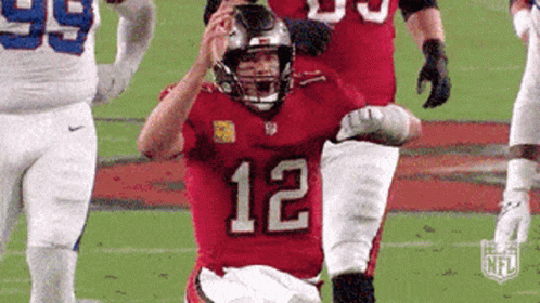 A Football Player With The Number 12 On His Jersey Is Running On The Field . GIF