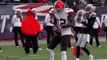 A Football Player With The Number 12 On His Jersey Is Running With The Ball On A Field . GIF
