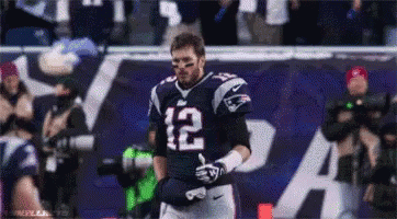 A Football Player With The Number 12 On His Jersey Stands On The Field . GIF