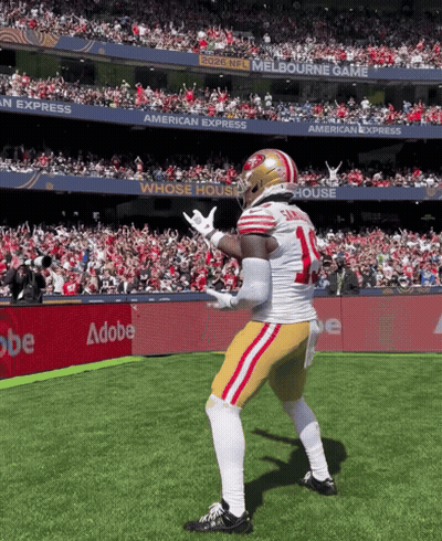A Football Player With The Number 14 On His Jersey Is Dancing On The Field GIF