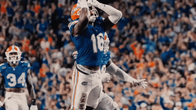 A Football Player With The Number 16 On His Jersey Is Catching A Pass In Front Of A Crowd . GIF