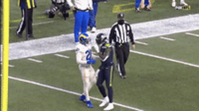 A Football Player With The Number 2 On His Jersey Is Running On A Field With A Referee . GIF