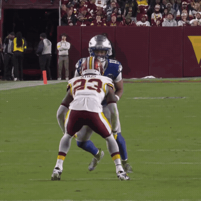 A Football Player With The Number 23 On His Jersey Is Being Tackled By Another Player GIF