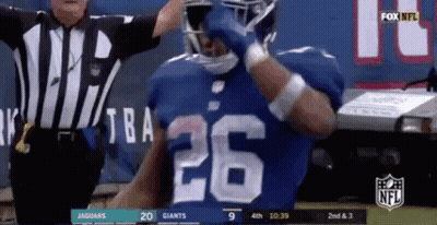A Football Player With The Number 26 On His Jersey Is Standing In Front Of A Referee . GIF