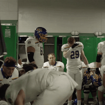 A Football Player With The Number 29 On His Jersey Stands In A Locker Room GIF