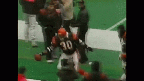 A Football Player With The Number 30 On His Jersey Is Running On A Field With A Football . GIF