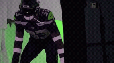 A Football Player With The Number 33 On His Jersey Is Standing In Front Of A Green Background . GIF