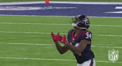A Football Player With The Number 34 On His Jersey Is Catching A Pass On A Field . GIF