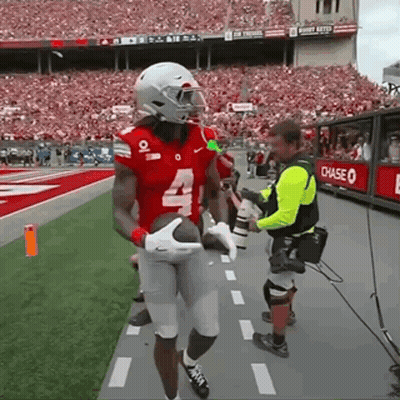 A Football Player With The Number 4 On His Jersey Is Holding A Football GIF