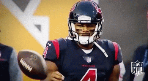 A Football Player With The Number 4 On His Jersey Is Holding A Football In His Hand . GIF
