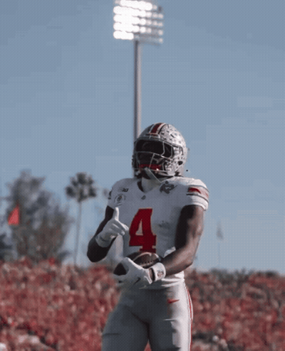 A Football Player With The Number 4 On His Jersey Is Holding A Football GIF