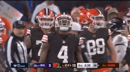 A Football Player With The Number 4 On His Jersey Stands With His Teammates GIF
