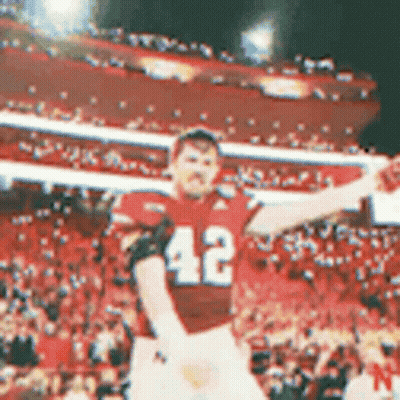 A Football Player With The Number 42 On His Jersey Is Standing In Front Of A Crowd . GIF