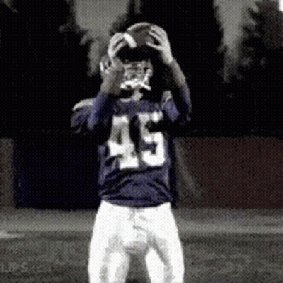 A Football Player With The Number 45 On His Jersey Is Holding A Football In His Hands . GIF