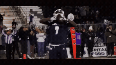 A Football Player With The Number 7 On His Jersey Stands In Front Of A Crowd GIF
