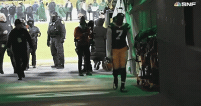 A Football Player With The Number 7 On His Jersey Walks Out Of A Locker Room GIF