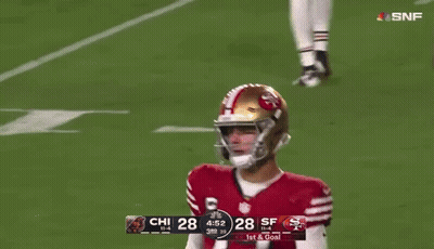 A Football Player With The Number 77 On His Jersey Stands Next To A Player With The Number 14 On His Jersey GIF
