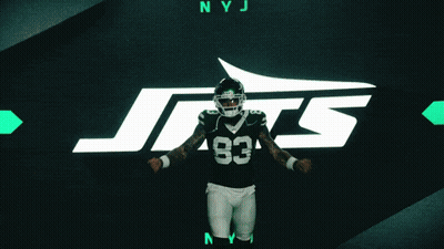 A Football Player With The Number 83 On His Jersey Stands In Front Of A Jets Logo GIF