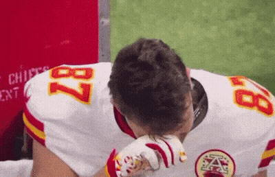 A Football Player With The Number 87 On His Jersey Wipes His Face GIF