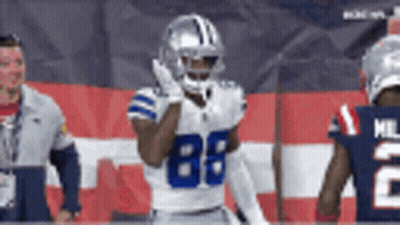 A Football Player With The Number 88 On His Jersey Stands In Front Of A Flag . GIF