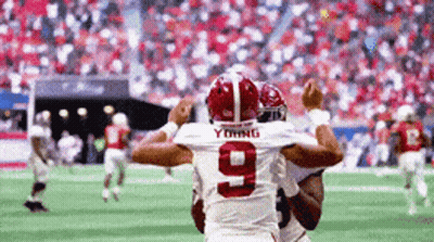 A Football Player With The Number 9 On His Jersey Is Being Hugged By Another Player On The Field . GIF