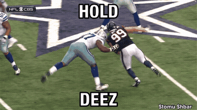 A Football Player With The Number 99 On His Jersey Is Being Tackled GIF