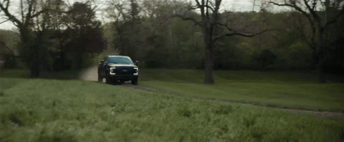 A Ford Truck Is Driving Down A Dirt Road GIF
