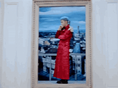A Framed Painting Of A Man In A Red Coat Standing In Front Of A City GIF