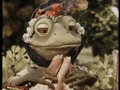 A Frog Wearing A Hat Is Holding A Woman 'S Leg GIF