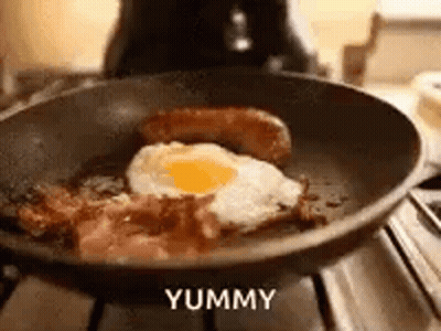 A Frying Pan Filled With Bacon , Eggs , And Sausage On A Stove . GIF