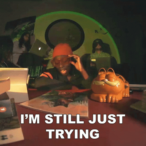 A Garfield Statue Sits On A Table Next To A Woman Wearing Sunglasses And A Sign That Says " To Make You Stay " GIF