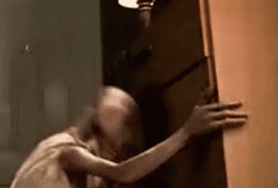 A Ghost Is Standing In A Doorway Holding A Door . GIF