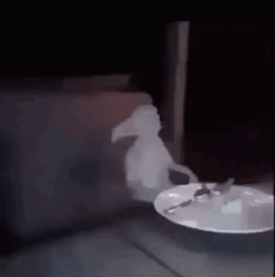 A Ghost Is Standing Next To A Plate Of Food With A Spoon On It . GIF