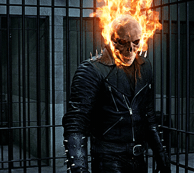 A Ghost Rider With Flames Coming Out Of His Head Stands In Front Of A Prison Cell GIF