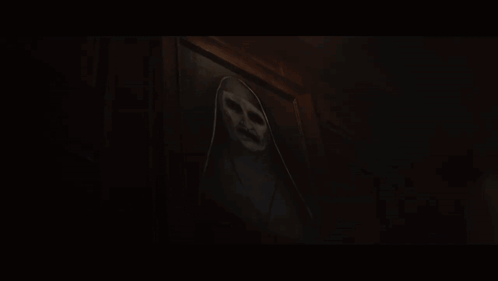 A Ghost With A Scary Face Is Behind A Door In A Dark Room GIF