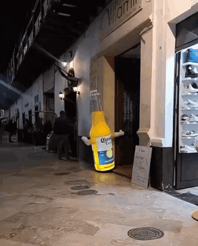 A Giant Bottle Of Corona Beer Is Sitting Outside Of A Store GIF