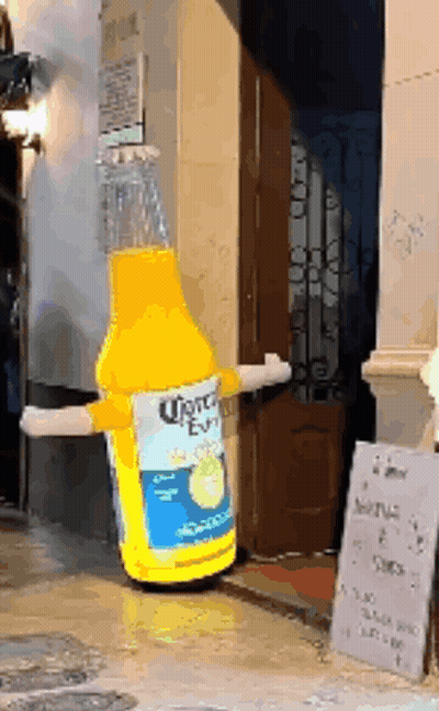 A Giant Inflatable Bottle Of Corona Beer Is Standing In Front Of A Building GIF
