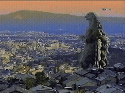 A Giant Monster Is Standing On Top Of A Rooftop Overlooking A City GIF