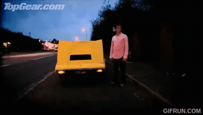 A Gif From Topgear.com Shows A Yellow Car Driving Down The Road GIF