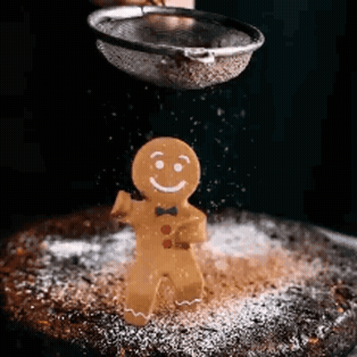 A Gingerbread Man Is Being Sprinkled With Powdered Sugar . GIF