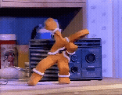 A Gingerbread Man Is Dancing In Front Of A Radio On A Table . GIF