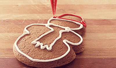 A Gingerbread Man Is Decorated With White Frosting And A Red Ribbon GIF